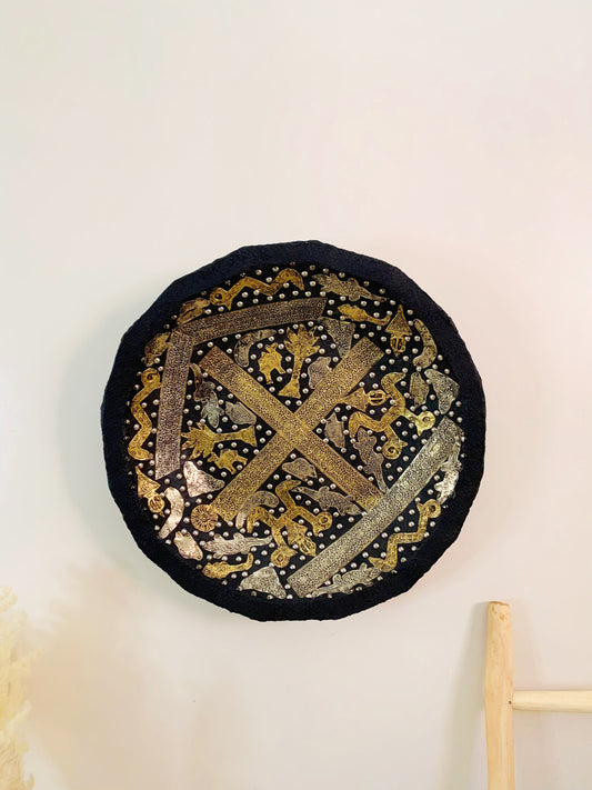 a black and gold plate hanging on a wall