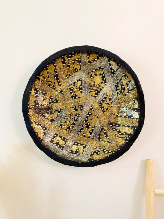 a black and gold plate hanging on a wall