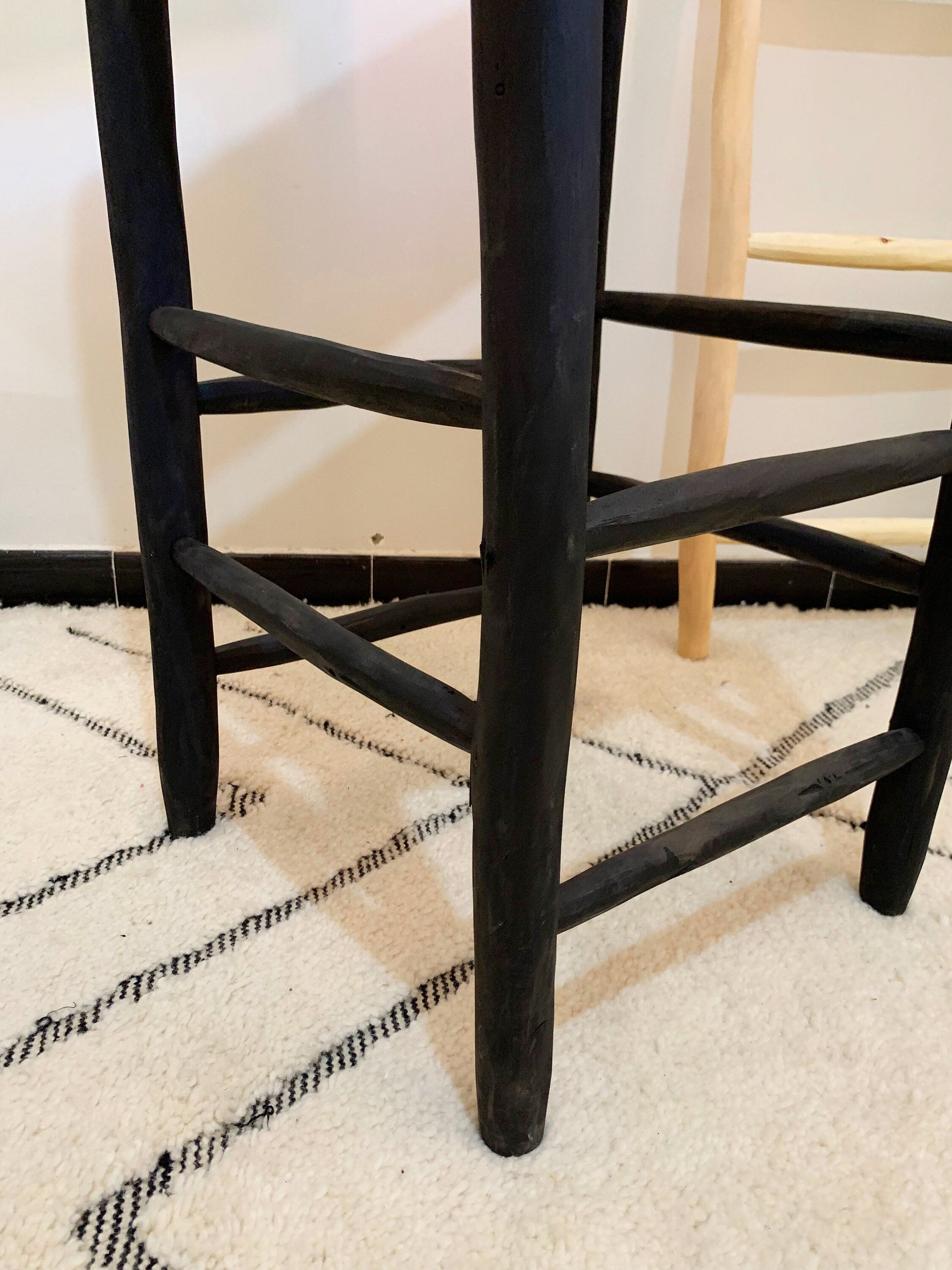 a wooden chair with a black seat on a white rug