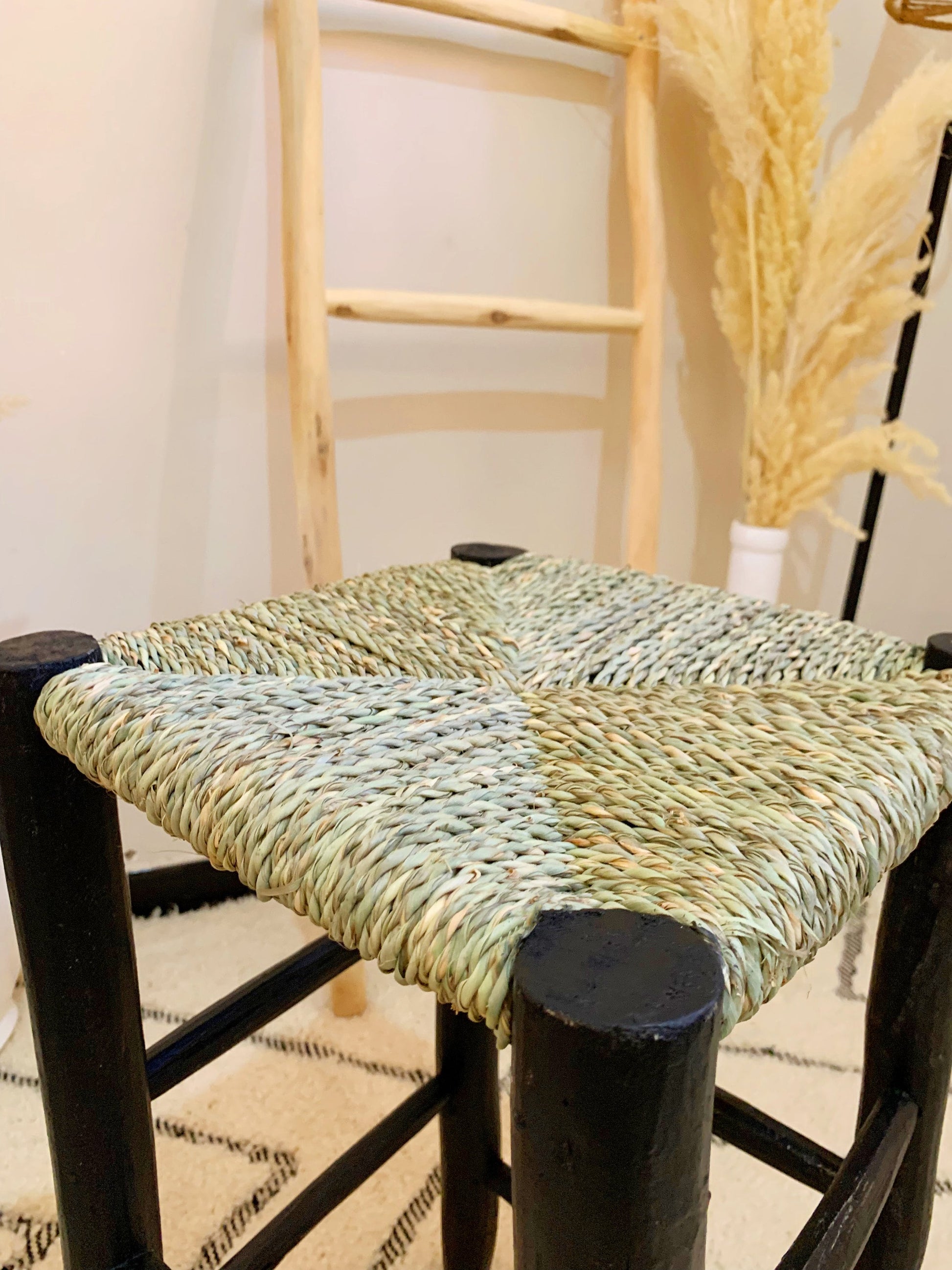 a chair with a woven seat and black legs